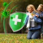 Happy mother with her son on green grass in autumn park. Strong immunity - shield against viruses