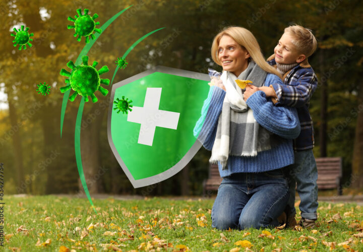 Happy mother with her son on green grass in autumn park. Strong immunity - shield against viruses