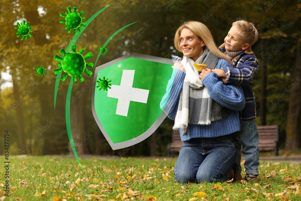 Happy mother with her son on green grass in autumn park. Strong immunity - shield against viruses